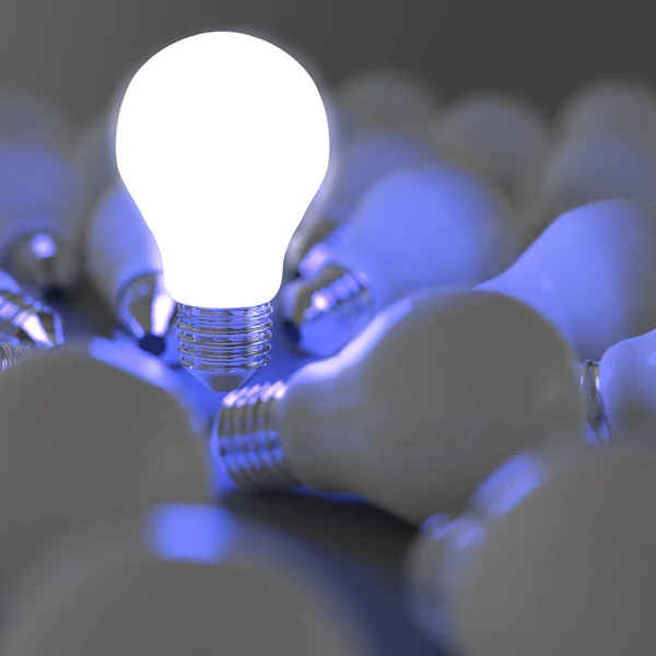 Growing light bulb standing out from the unlit incandescent bulb — Stock Photo, Image