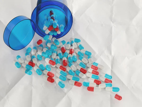 Pillen aus Tablettenflasche auf zerknülltem Papier verschüttet — Stockfoto