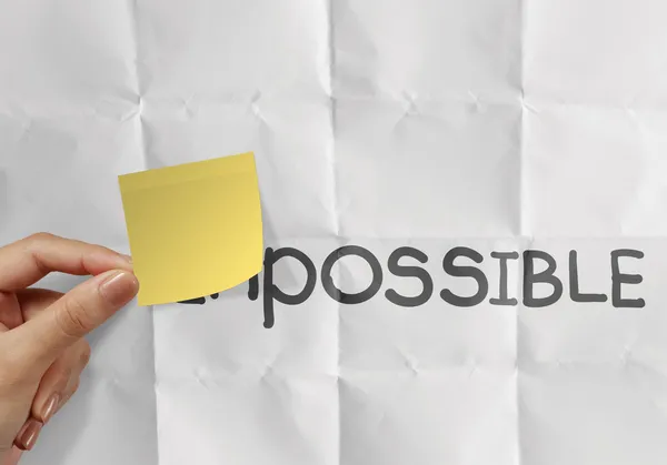 Hand holding sticky note over word impossible transformed into p — Stock Photo, Image