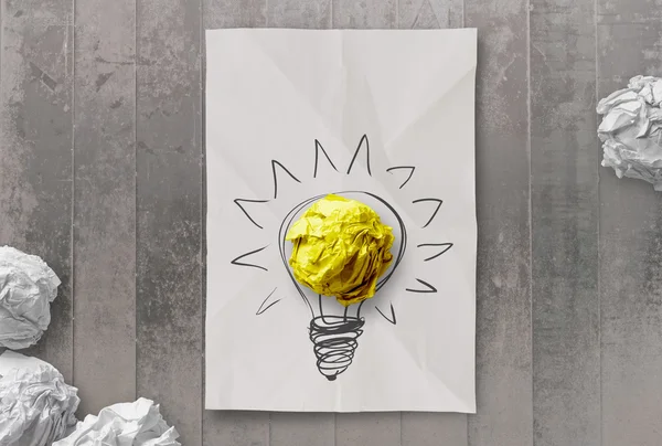 Tekening gloeilamp op verfrommeld papier met werkplek als creatief — Stok fotoğraf