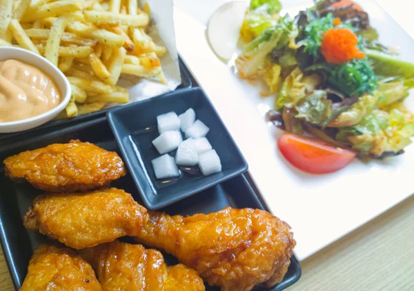 Fried drumsticks with french fries on wooden table top — Stock Photo, Image