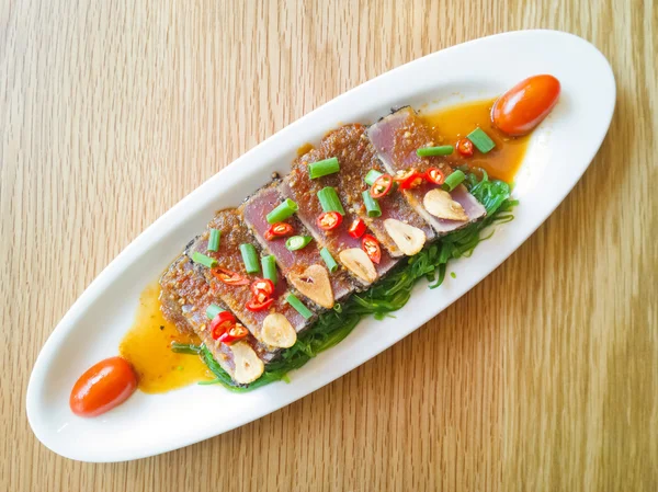 Affumicare il tonno piccante con fregio di insalata sul tavolo di legno — Foto Stock