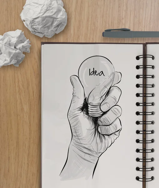 Lâmpada desenhada à mão com palavra IDEA no livro de notas no topo de madeira — Fotografia de Stock