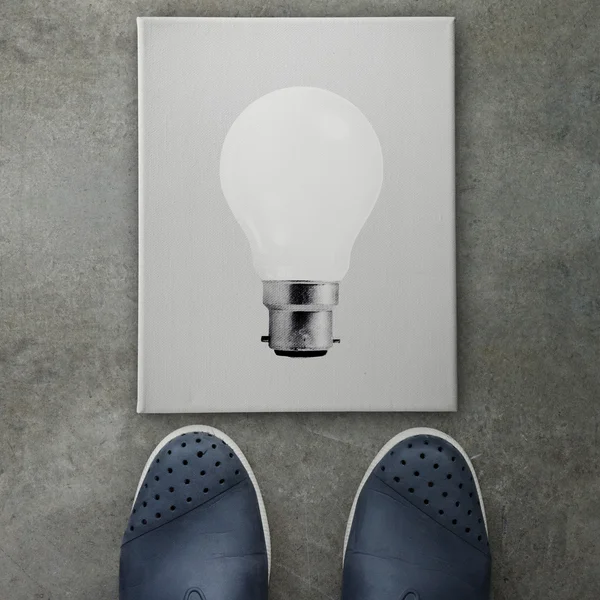 Hand drawn light bulb on dark canvas board front of business man — Stock Photo, Image