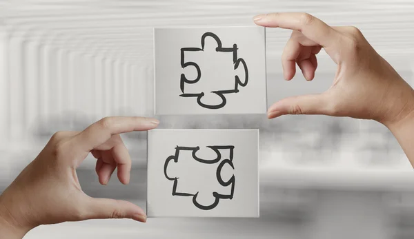 Mão segurando mão desenhada parceria Puzzle ícone na placa cavas — Fotografia de Stock