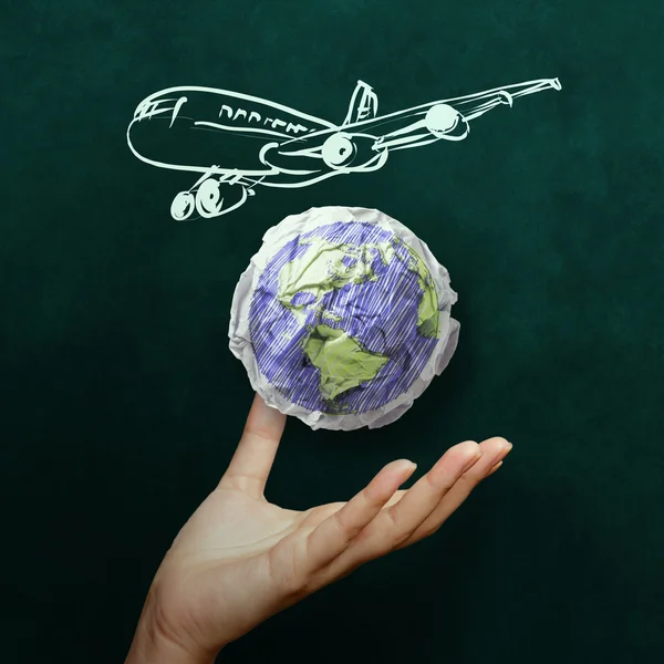 Hand zeigt Flugzeug mit zerknülltem Weltpapiersymbol als Konzep — Stockfoto
