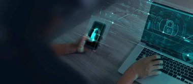 Siber güvenlik ve veri koruma bilgileri gizlilik internet teknolojisi kavramı. Akıllı telefon modern bilgisayar üzerinde çalışan iş adamı, sanal ağ bağlantısı ile iş ve mali verileri koruyan asma kilit gösteriyor..