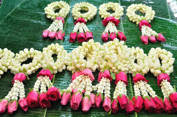 Ghirlanda di gelsomino da vicino con rosa rosa su foglia di banana — Foto Stock