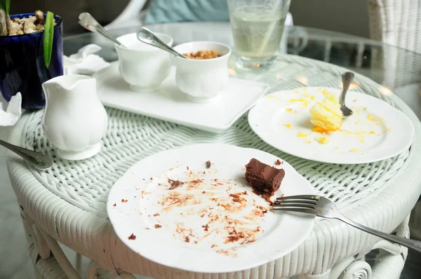 Soiled cake plates on rattan table — Stock Photo, Image