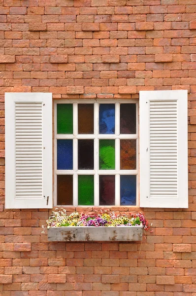 Finestra bianca sul muro di mattoni rossi e vetro di colore appendere vaso di fiori — Foto Stock