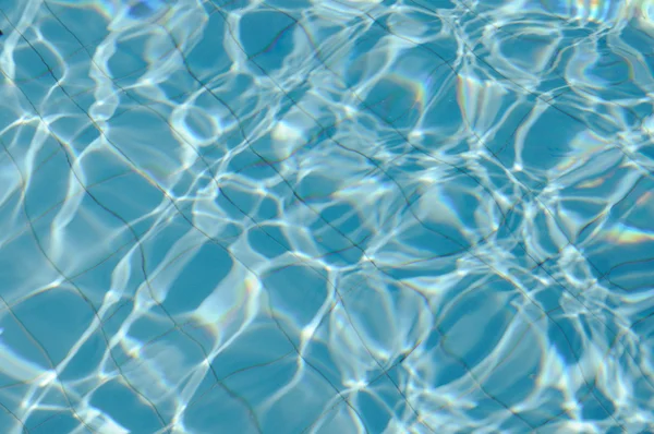 Água rasgada azul na piscina com reflexos ensolarados — Fotografia de Stock