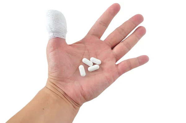 Medicines pill in hand with thumb bandage — Stock Photo, Image