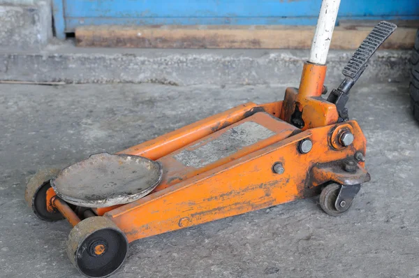 Short orange screw jack on concrete — Stock Photo, Image