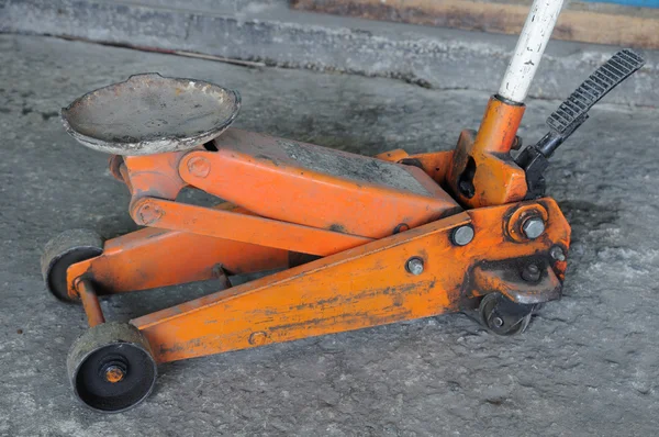Short orange screw jack on concrete — Stock Photo, Image