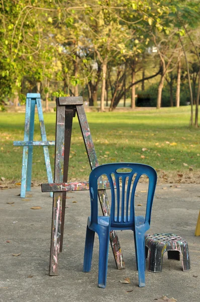 Vari cavalletti in legno con sedie in plastica nel giardino pubblico — Foto Stock