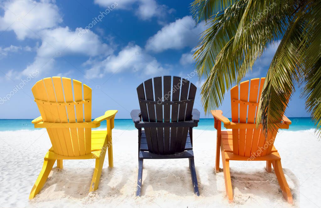 Three colorful beach chairs under palm tree