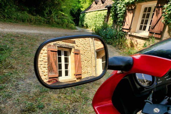 French country cottage reflected in a motorbike wing mirror, parked outside of a French farmhouse