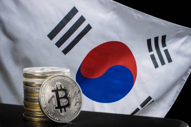 Bir gümüş bitcoin ve Güney Kore bayrağı üzerinde bitcoin yığını
