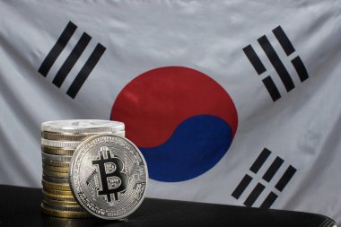 Bir gümüş bitcoin ve Güney Kore bayrağı üzerinde bitcoin yığını