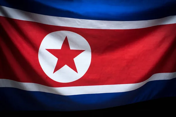 Waving flag of North Korea over dark background