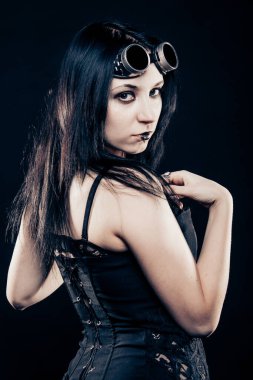 Karanlık arka planda poz veren oldukça baştan çıkarıcı gotik bir kız.