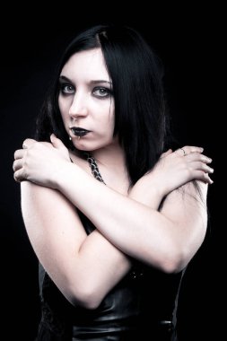 Karanlık arka planda poz veren oldukça baştan çıkarıcı gotik bir kız.