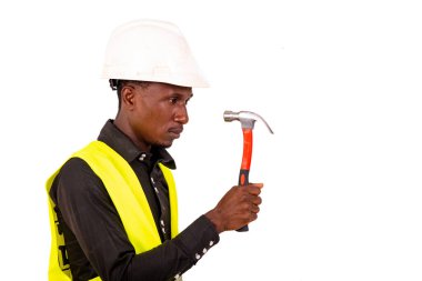 Yeşil yelek giyen, kasklı ve elinde tornavida tutan genç bir erkek teknisyen..