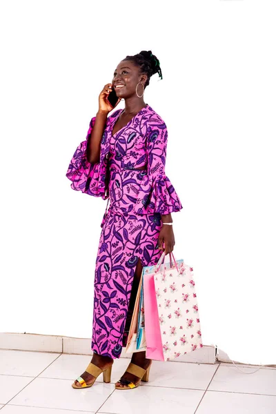 Geleneksel peştemalle gezen genç ve güzel bir iş kadını alışveriş torbaları tutuyor ve gülümserken cep telefonuyla konuşuyor..