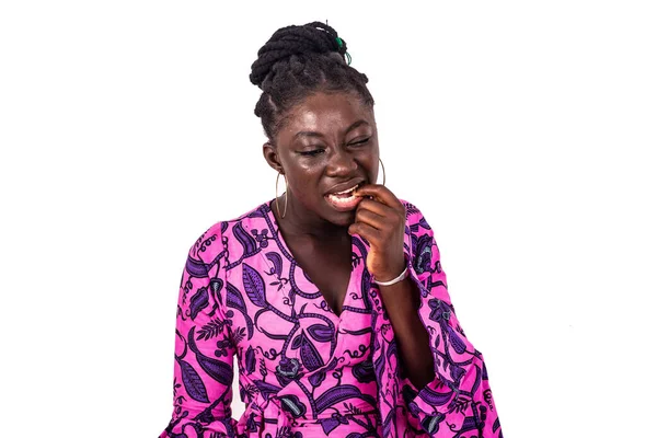 Geleneksel kıyafetli güzel bir Afrikalı kadın beyaz arka planda durup parmağını ısırıyor..
