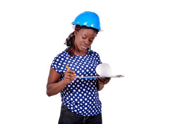 Genç bayan inşaat mühendisi mavi şapka takıyor ve panoda notlar okuyor..