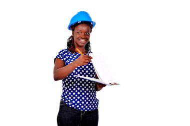 Genç bayan inşaat mühendisi mavi bir şapka takıyor ve gülümserken panodaki notları kontrol ediyor..