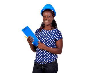 Genç bayan inşaat mühendisi mavi şapka takıyor ve elinde bir pano tutarken gülümsüyor..