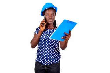 Genç bayan inşaat mühendisi elinde bir pano ve cep telefonuyla konuşuyor..