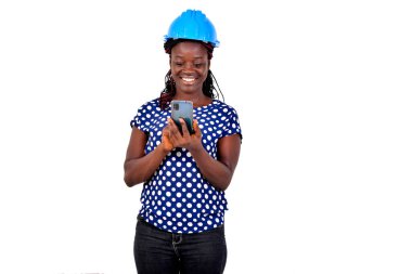 Mavi kasklı güzel bir bayan mühendisin portresi ve gülümserken cep telefonuyla çalışması..