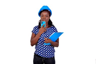 Güzel genç bayan inşaat mühendisi elinde bir cep telefonu ve bir pano tutarken düşünüyor..