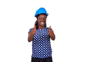 Güzel, mutlu, genç bir kadın mühendisin portresi mavi güvenlik kaskı takıyor ve gülümserken başparmağını kaldırıyor..