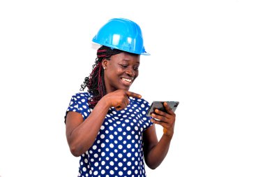 Mavi kasklı genç bayan mühendis video izlerken cep telefonu ekranını işaret ediyor..