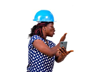 Güvenlik kasklı güzel bir bayan mühendis beyaz arka planda duruyor ve cep telefonuyla konuşuyor..