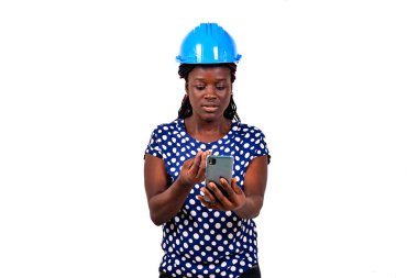 Güvenlik kasklı güzel bir bayan mühendis beyaz arka planda duruyor ve cep telefonuyla konuşuyor..
