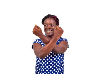 Güzel, genç ve mutlu bir kadının portresi beyaz arka planda duruyor ve iki koluyla çapraz hareket yapıyor ve gülümsüyor..