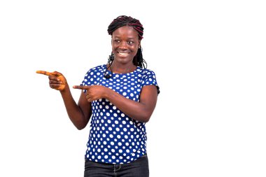 Güzel bir genç kadın portresi beyaz arka planda duruyor ve gülümserken parmaklarını kenarı gösteriyor..