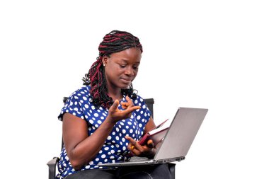 Evde bir sandalyede oturmuş dizüstü bilgisayar ve not defteri kullanarak çalışan güzel bir iş kadını..