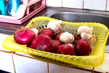 Mutfak lavabosunda içinde soğan ve sarımsak olan bir sepet..