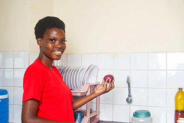 Linda Menina Vestindo Camiseta Vermelha Segurando Cebola Cozinha Enquanto Sorri — Fotografia de Stock