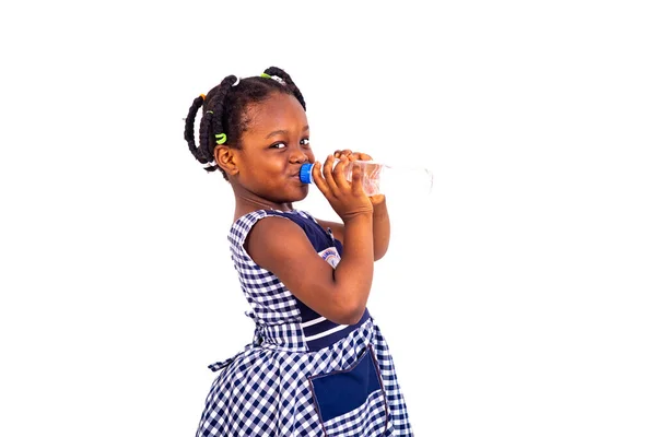学校の服を着た可愛い女の子がペットボトルからミネラルウォーターを飲んで — ストック写真