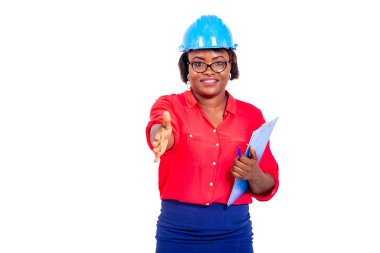 Güzel bayan mühendis mavi güvenlik kaskı takıyor, panoyu tutuyor ve gülümserken el sıkışmayı teklif ediyor..