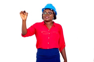 Güzel, yetişkin kadın mühendis mavi güvenlik kaskı takıyor ve boş uzaya bir kalemle yazarken gülümsüyor..