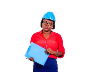 Güzel, yetişkin bir kadın mühendisin portresi mavi güvenlik kaskı takıyor ve elinde kalemle pano tutuyor..