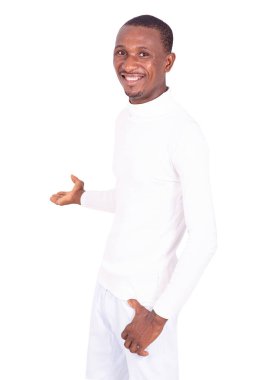 Beyaz elbiseli yakışıklı genç adam ellerini yana uzatıyor ve kameraya gülümsüyor..