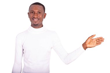 Beyaz giysili yakışıklı genç adam, elini kaldırıyor ve kameraya gülümsüyor..